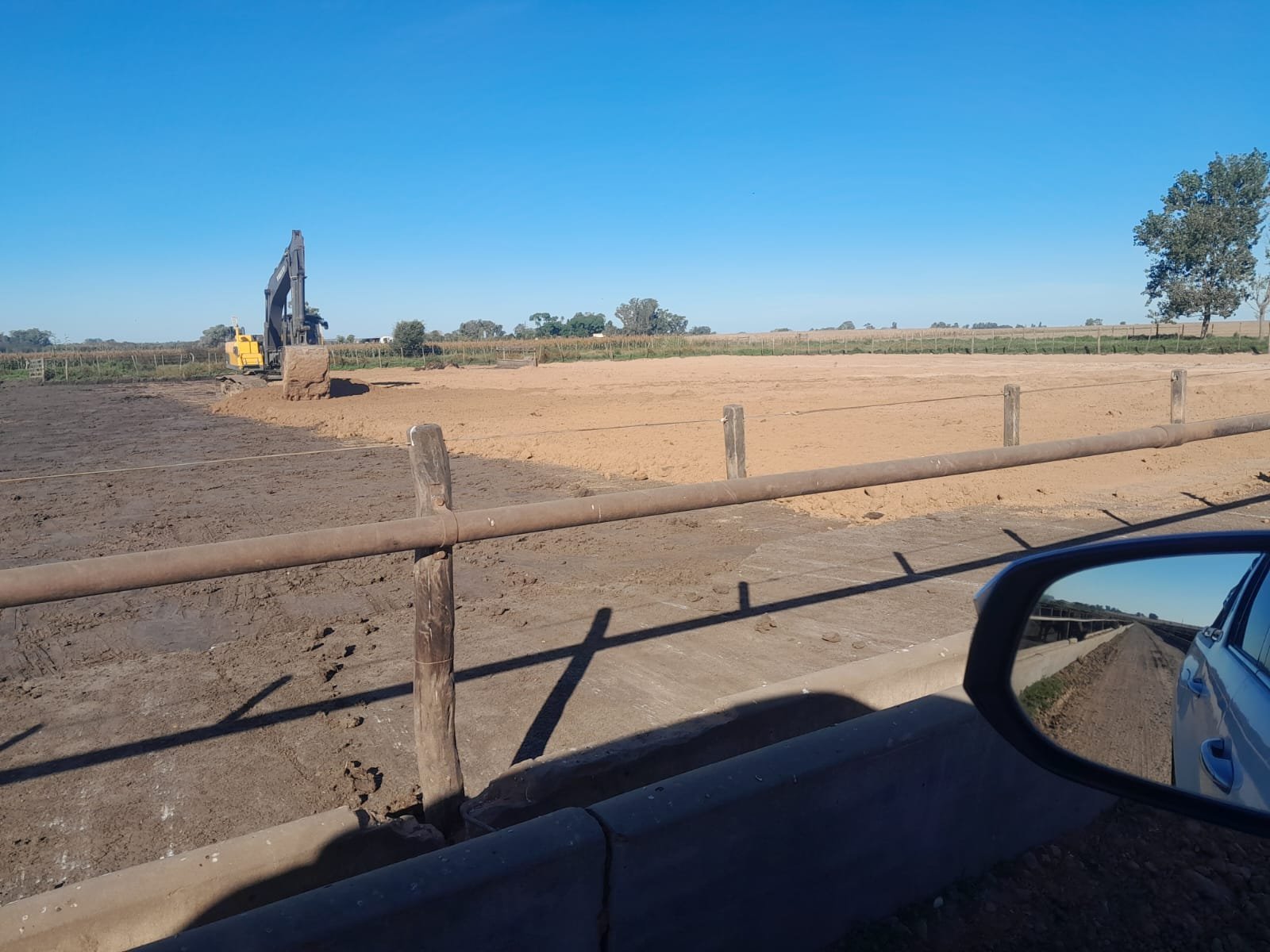 Excavadora trabajando en un terreno de tierra bajo un cielo despejado, obra de gestión ambiental y adecuación de suelos.